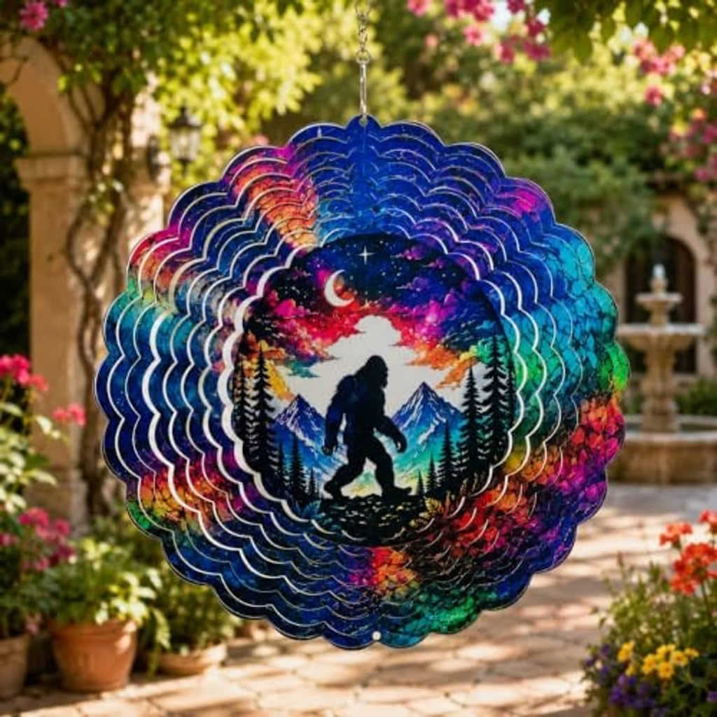 Front view of hanging Bigfoot wind spinner with moon, mountains, and pine trees
