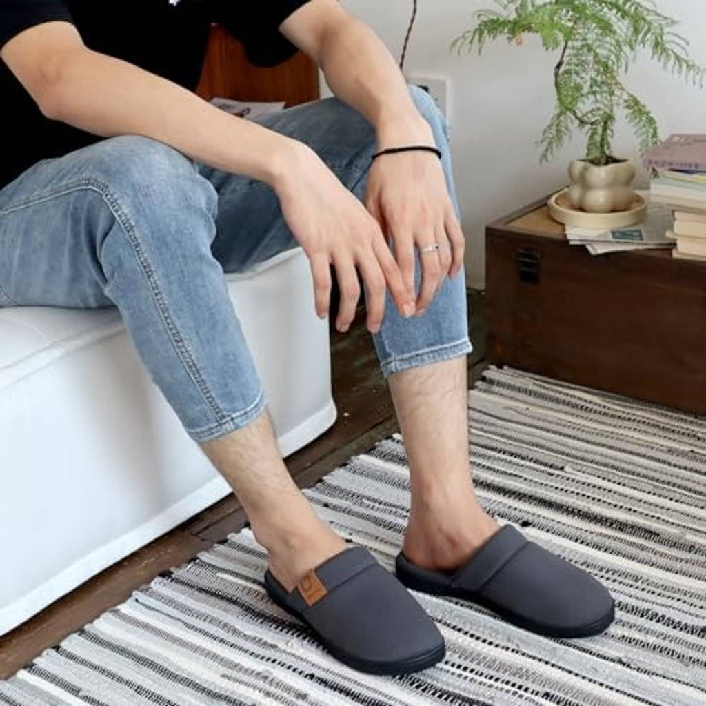 Men wearing dark gray slip-on slippers with plush lining over denim pants