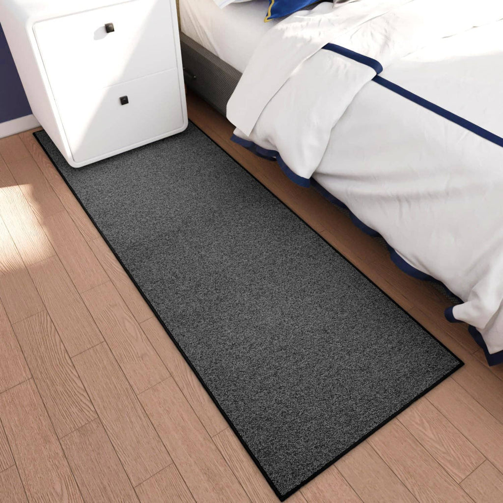 Charcoal gray runner rug along bed edge on hardwood floor with black border