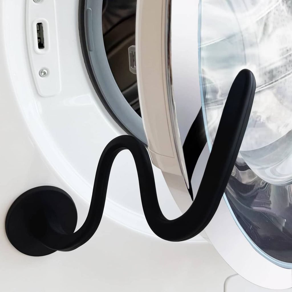 Black flexible washer door prop with suction-style base holding door ajar