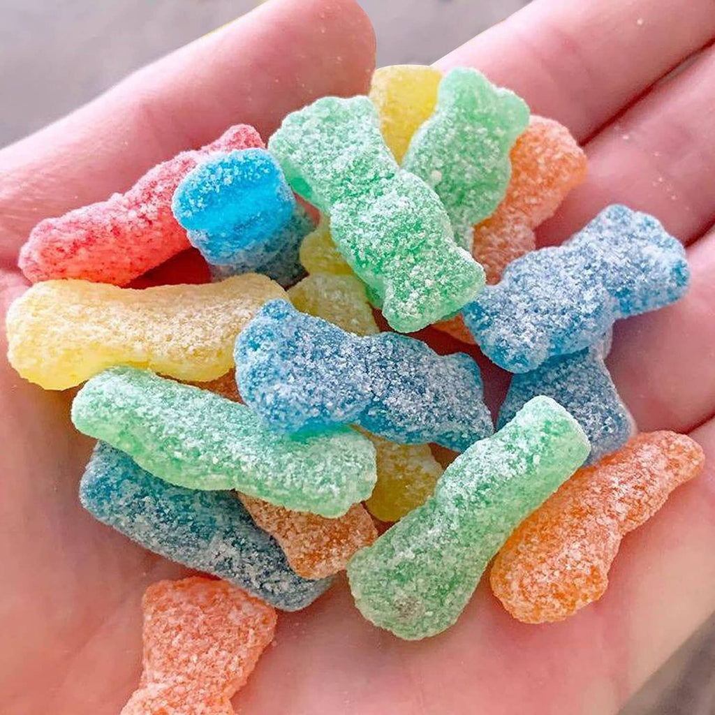 Hand holding assorted sour soft candy gummies in bright blue, green, orange, and red