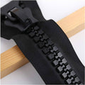 Black plastic zipper on woven tape with large pull and visible teeth.