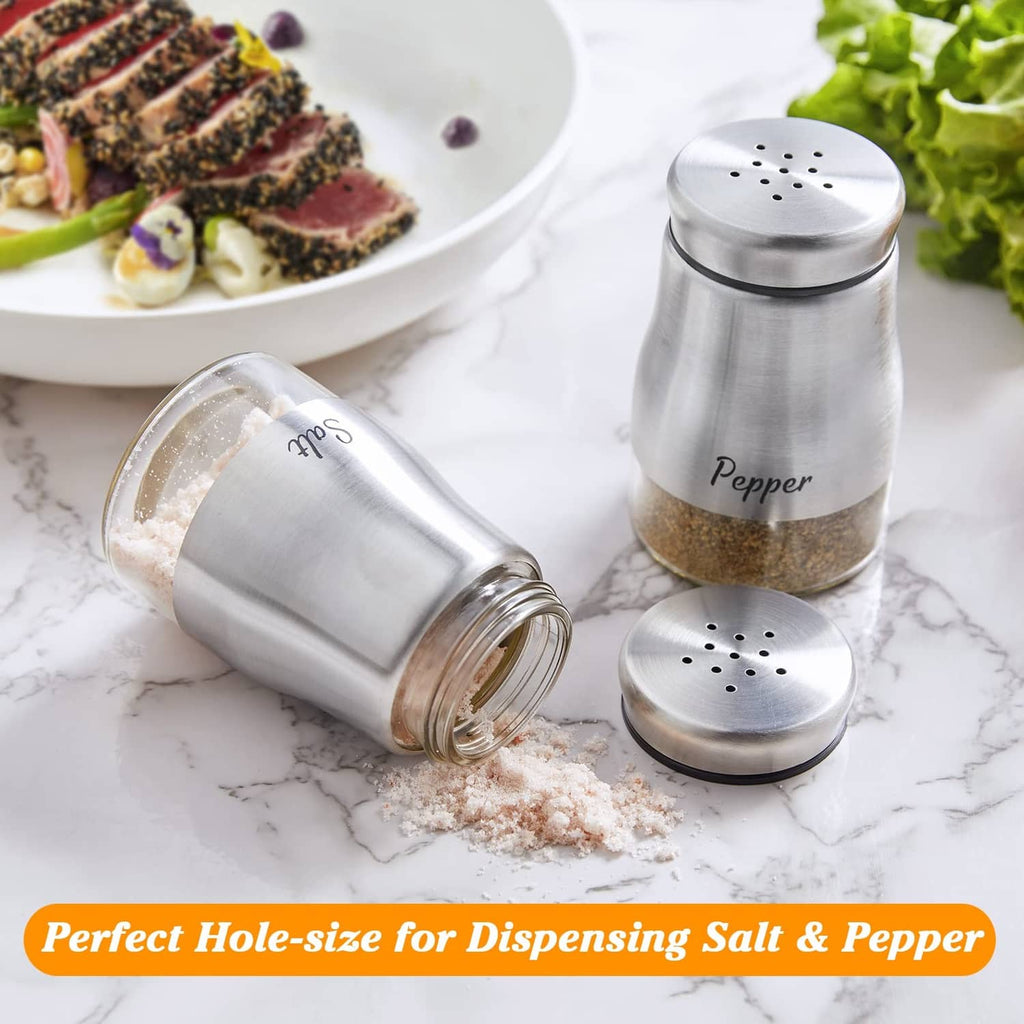 Stainless steel salt and pepper shakers, with one shaker tipped and seasoning spilled.