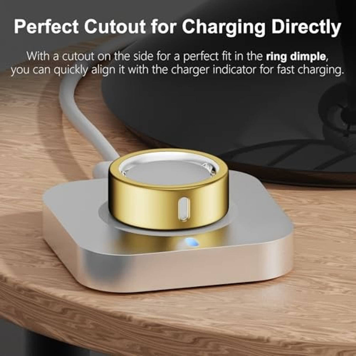 Gold-tone Oura ring cover with side cutout for charging indicator on a ring base