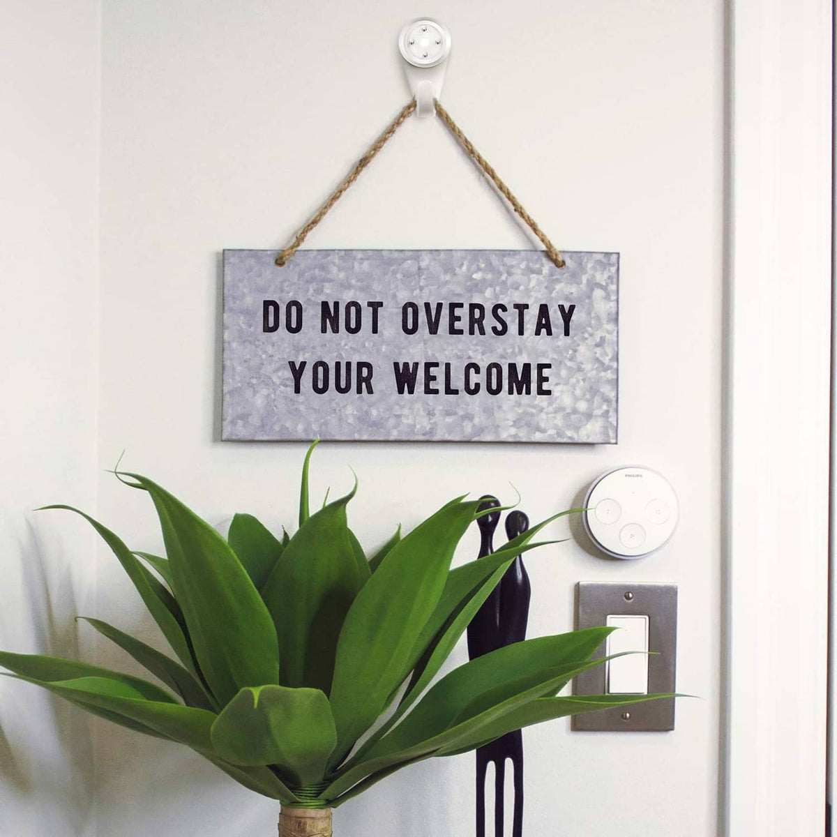 White plastic wall hook supporting rope-hung sign and keys