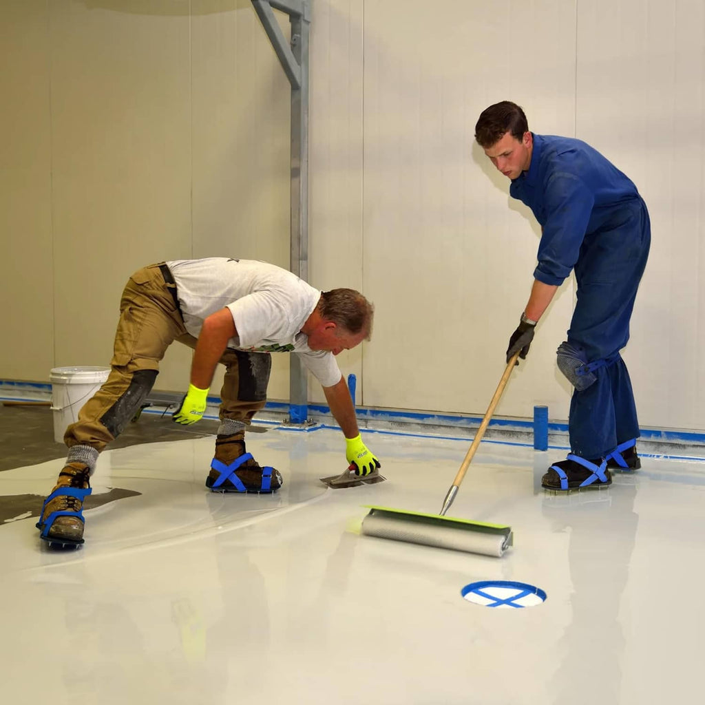 Workers applying epoxy wearing tan spiked shoes with blue straps and metal studs