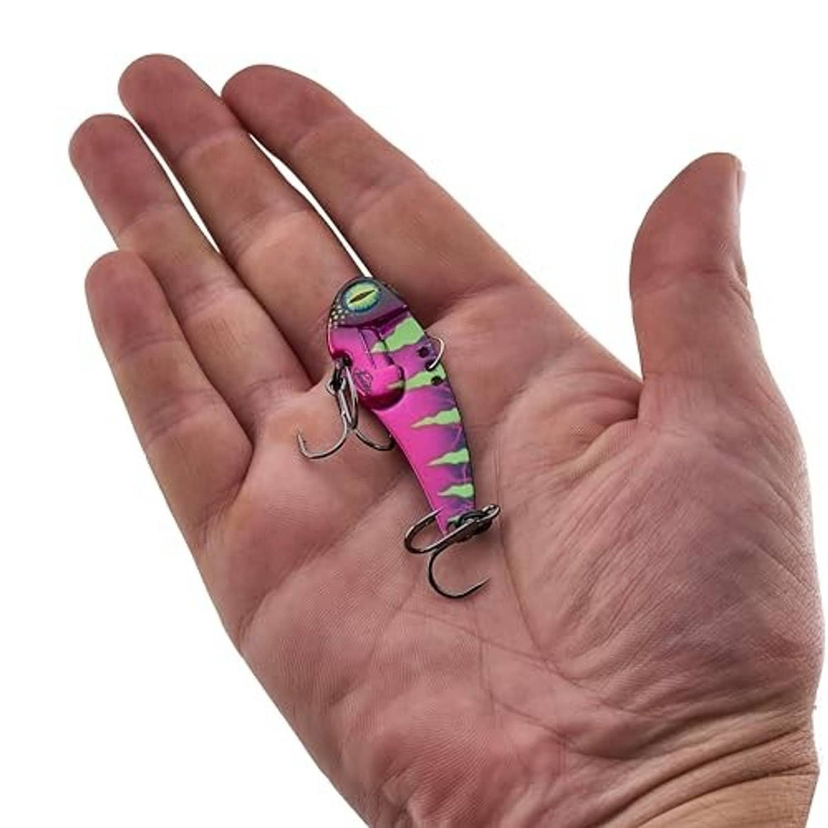 Fishing lure held in open palm; pink and green anaconda blade bait with treble hooks