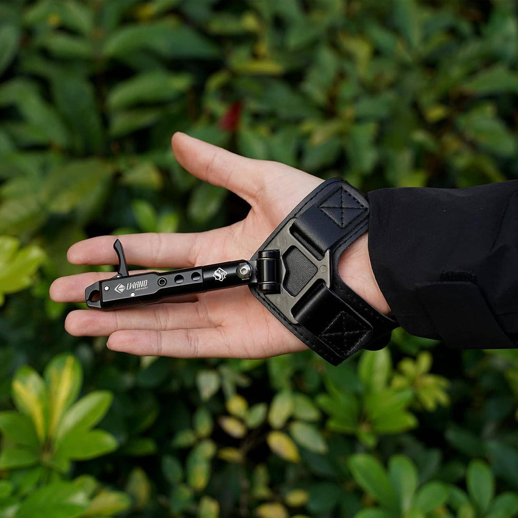 Black archery wrist release aid with padded strap and rotating trigger head in hand.