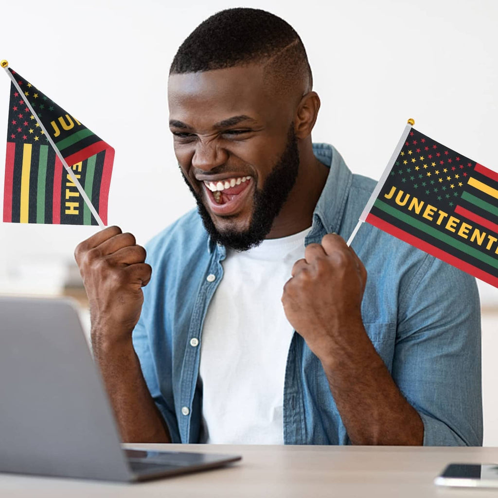 Smiling person holding Juneteenth mini flag with multicolor stripes, stars, and “JUNETEENTH”