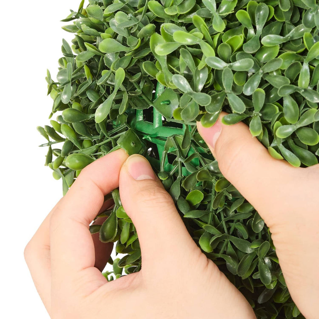 Artificial bunny-shaped boxwood ball, hands adjusting dense green leaf foliage