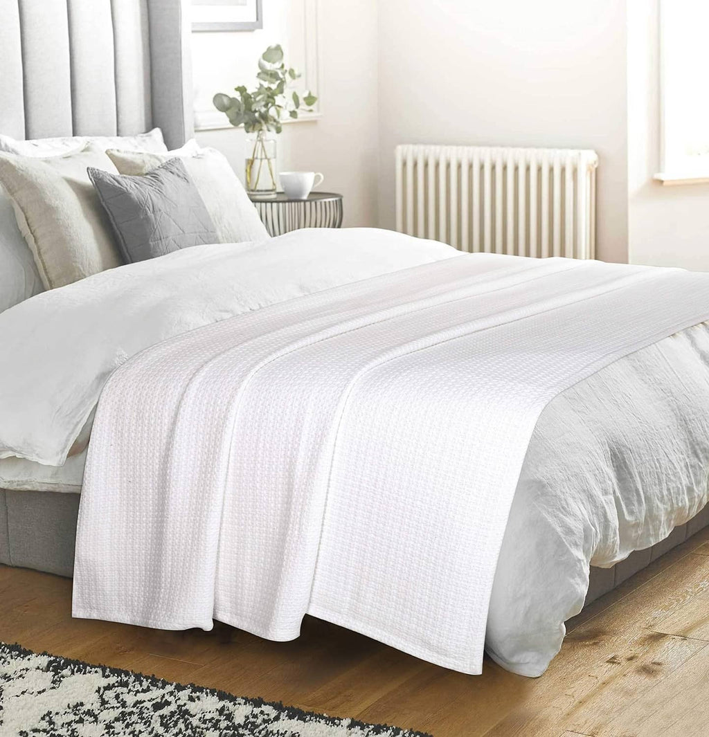 White waffle-weave bed blanket spread across bed surface.
