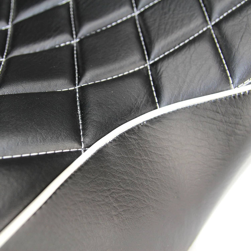 Close-up of black quilted seat surface with white stitched seams and curved piping trim.