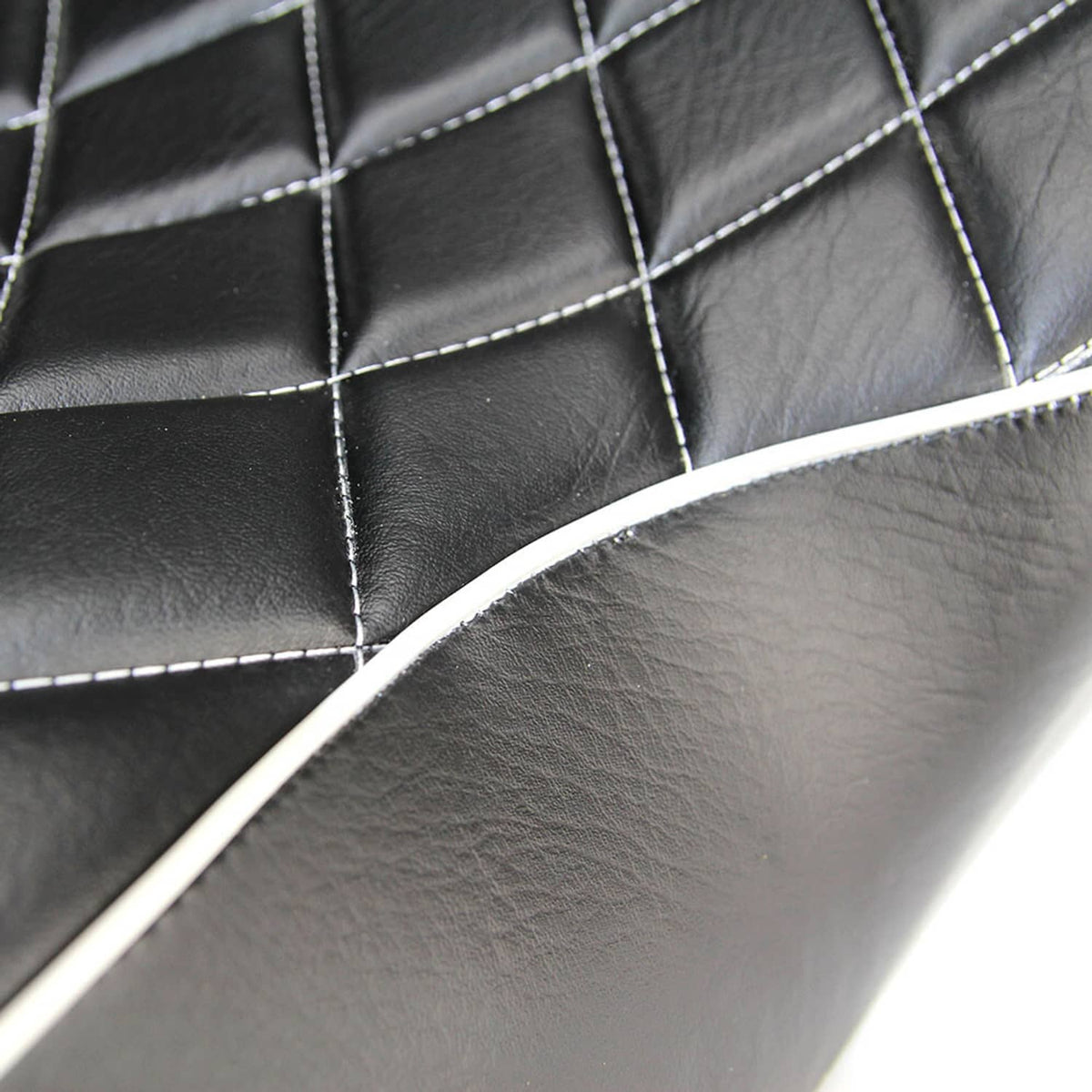 Close-up of black quilted seat surface with white stitched seams and curved piping trim.