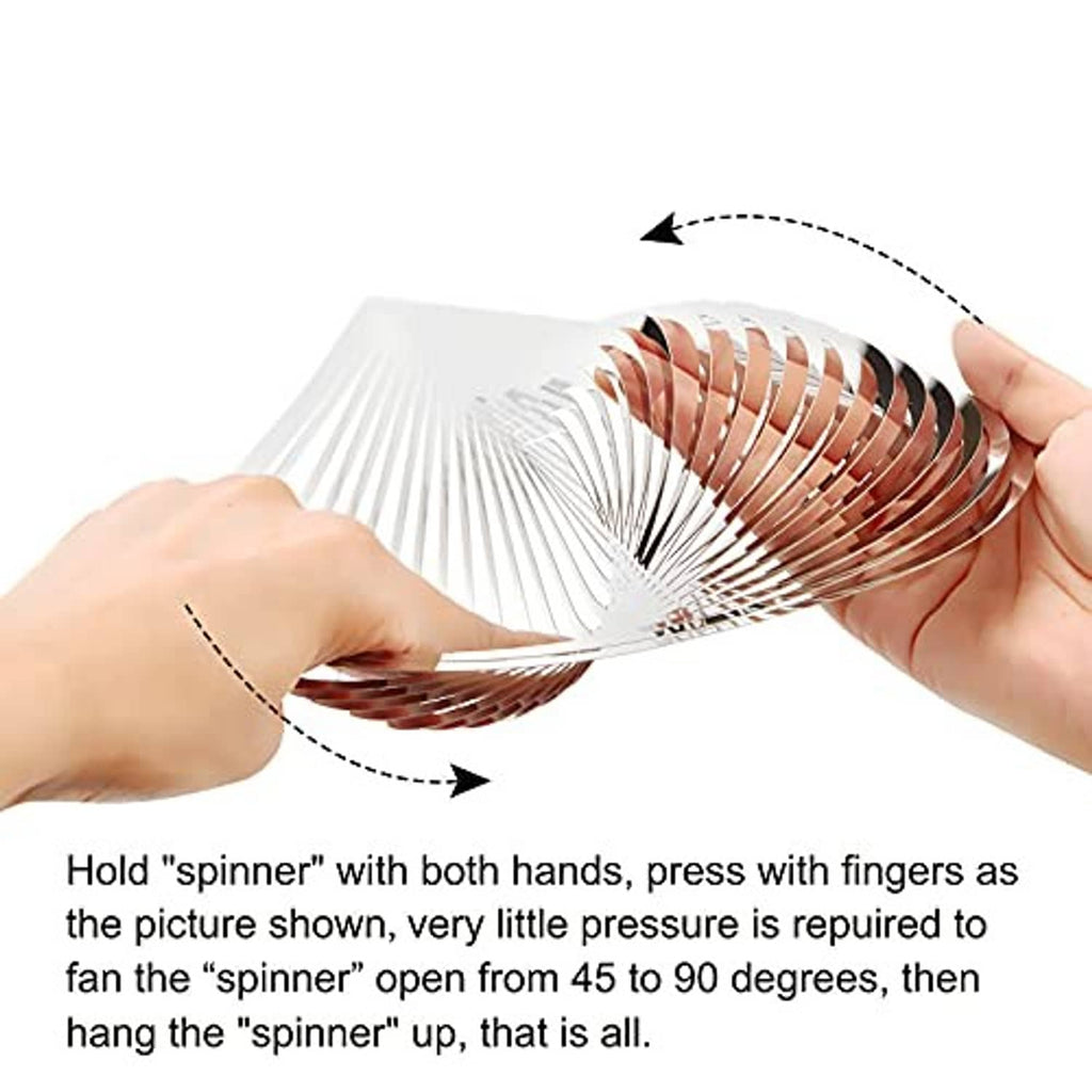 Stainless wind spinner being opened and fanned by hands, showing spiral slats