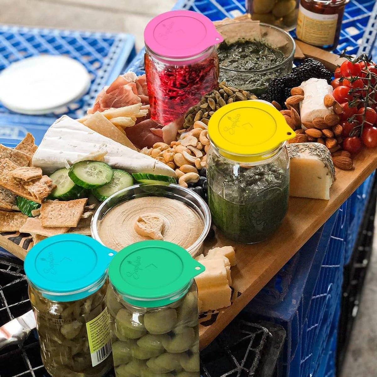 Silicone fermenting lids in green, pink, and yellow on mason jars filled with foods.