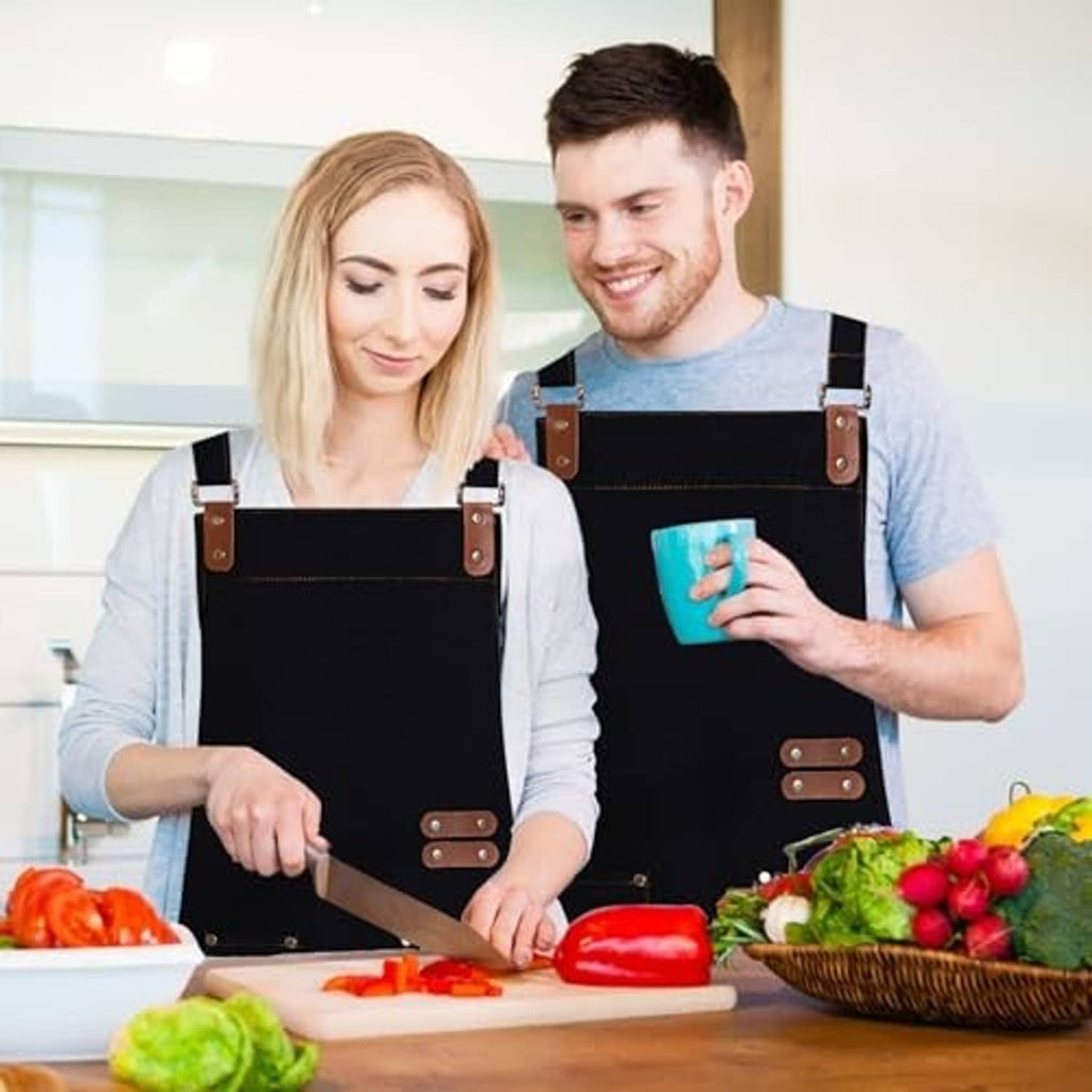 Black chef apron with adjustable brown leather straps and front utility pocket