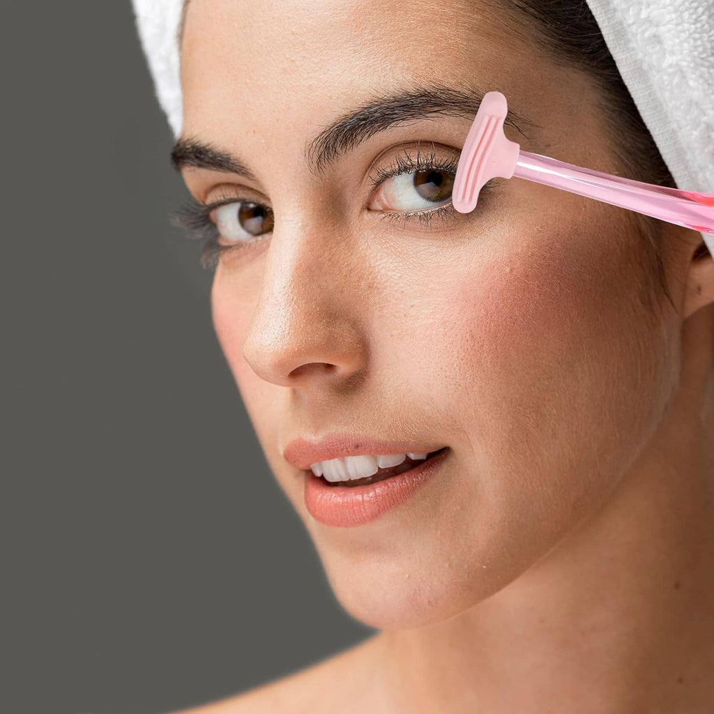 Pink eyelid cleansing brush positioned at the lash line in a close-up