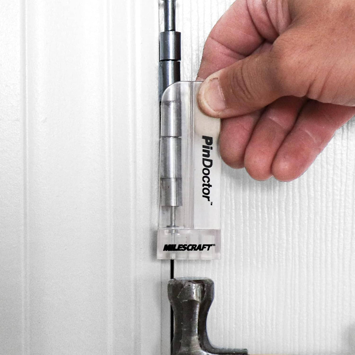 Pin locator tool held to a white door or cabinet panel for hinge positioning