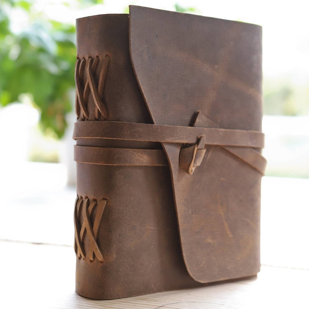 Brown leather journal notebook with embossed detailing and wrap strap closure.