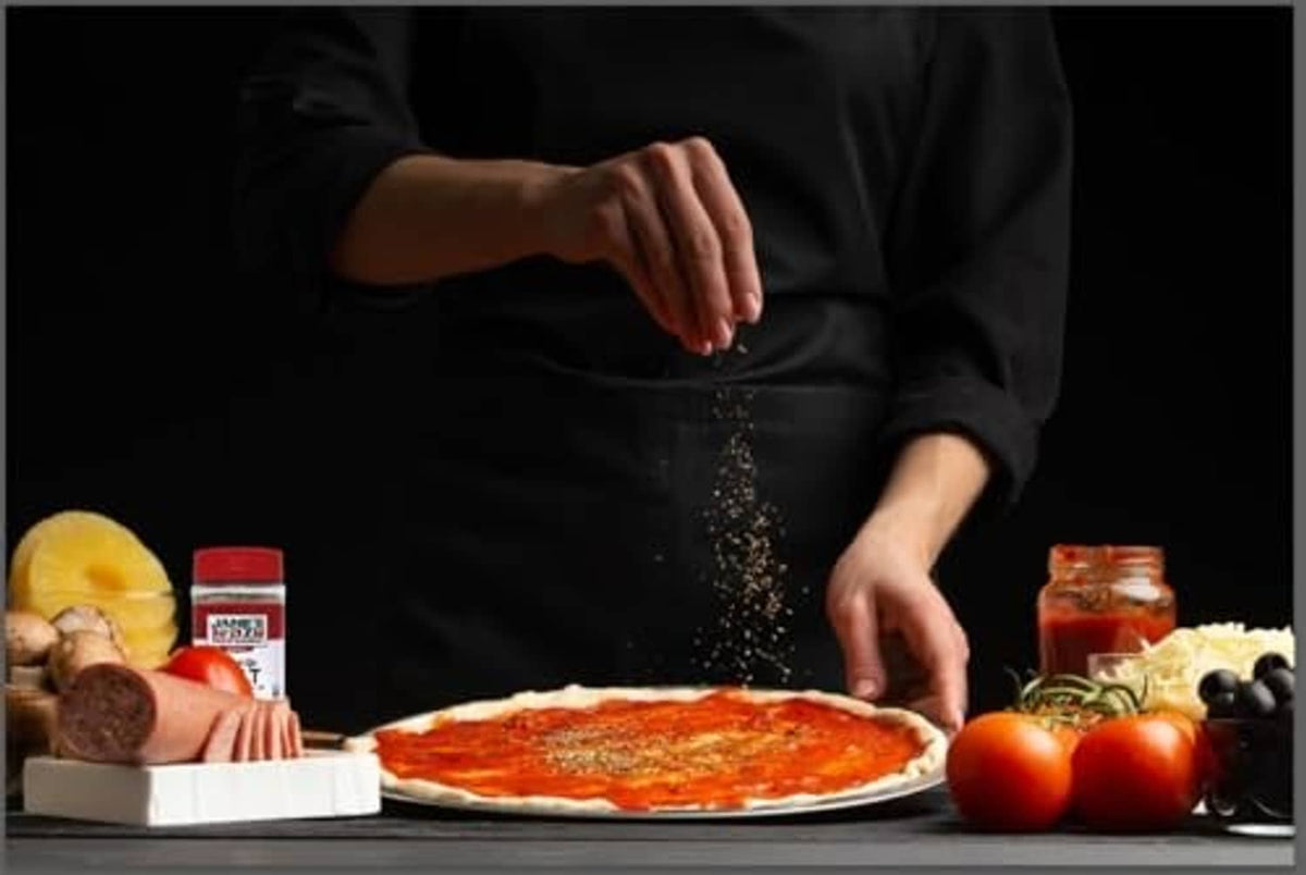 Hands sprinkling mixed-up seasoning over food; salt and pepper jars nearby