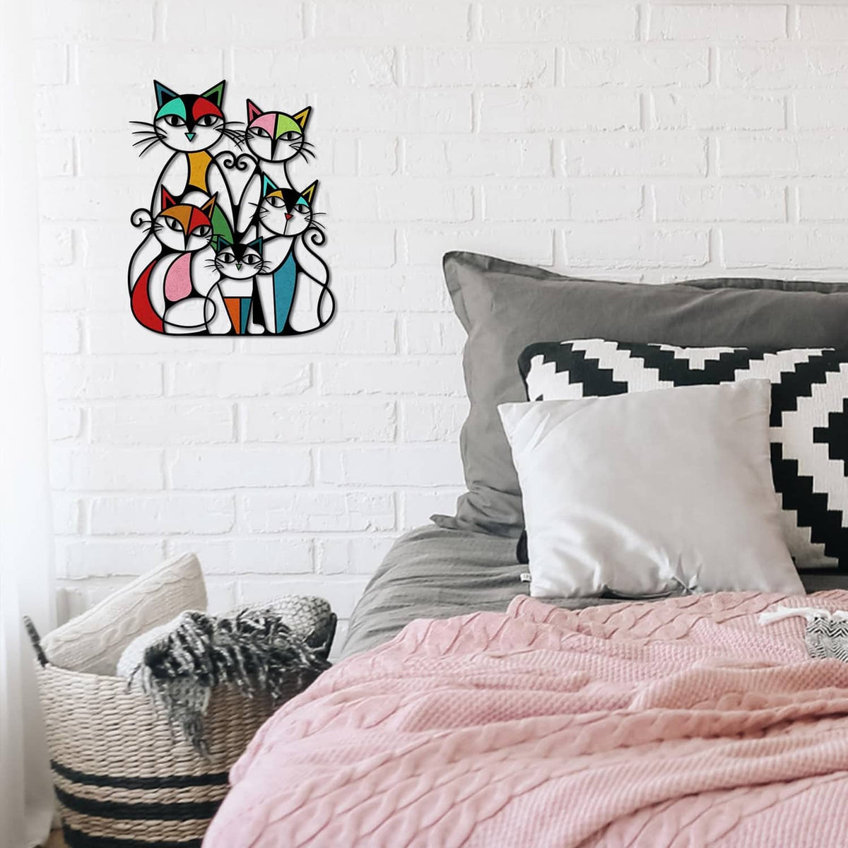 Colorful metal cat wall art with five retro cats above a bed with pillows