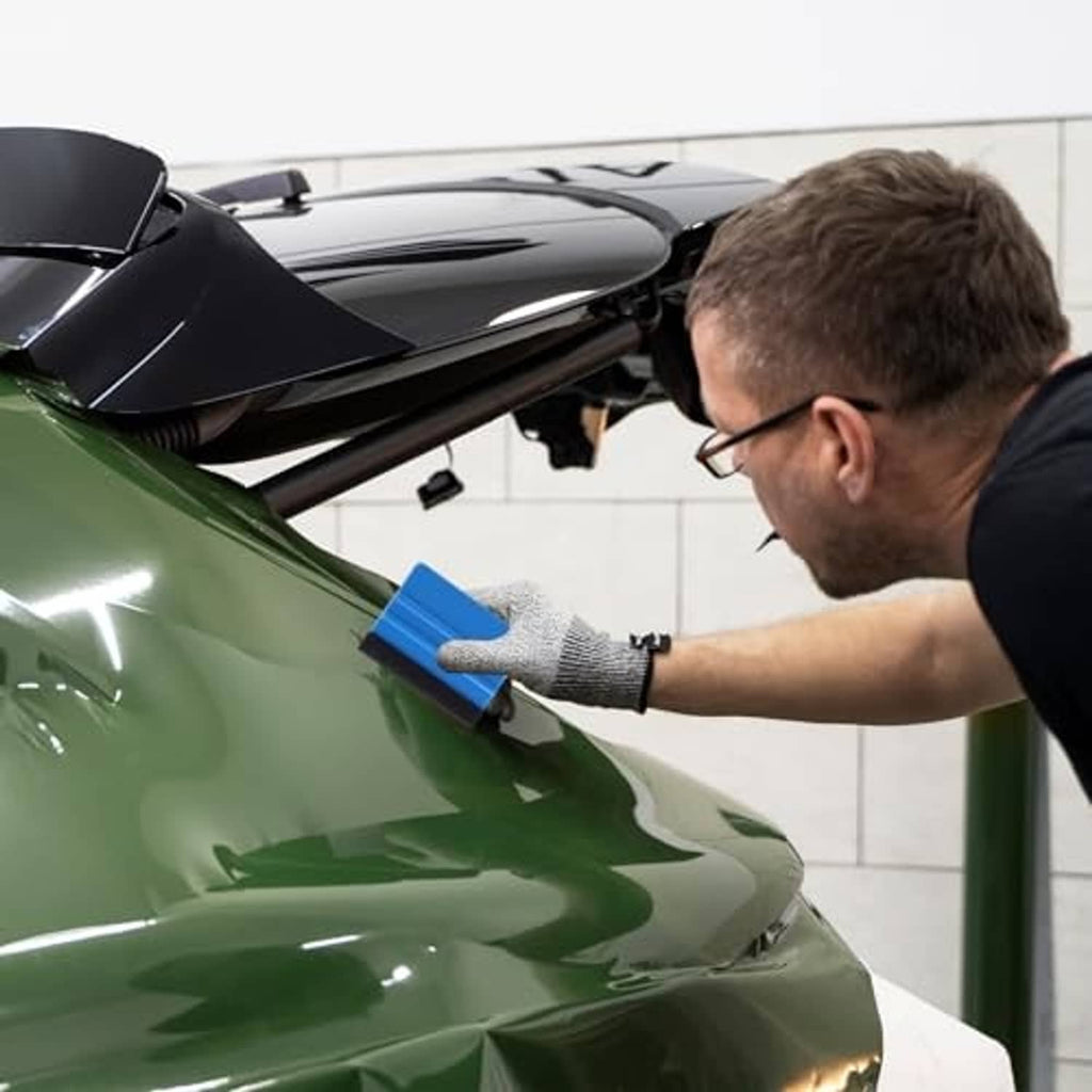Hand applying a blue felt squeegee to a car film surface