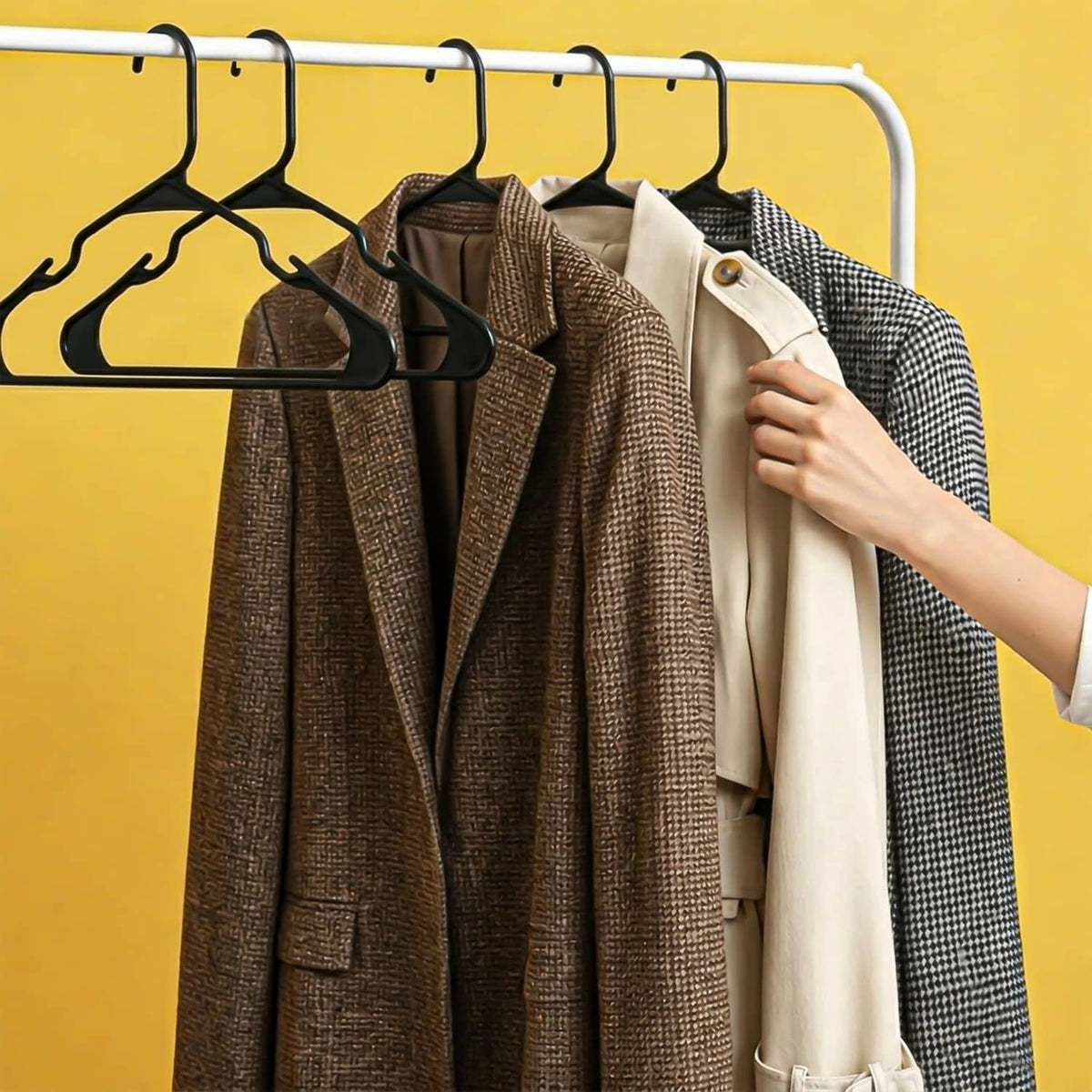 Black plastic hangers on a rail holding multiple coats and jackets.