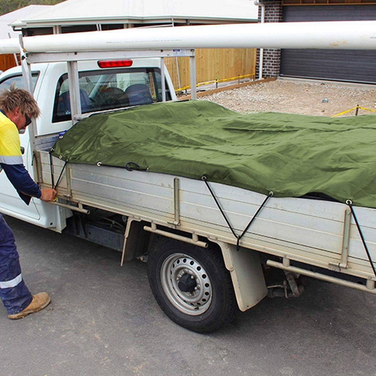 Green tarp laid over truck bed, fastened with tie loops and grommets along edges