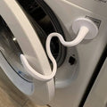 White front-load washer door prop, curved handle holding the door slightly open
