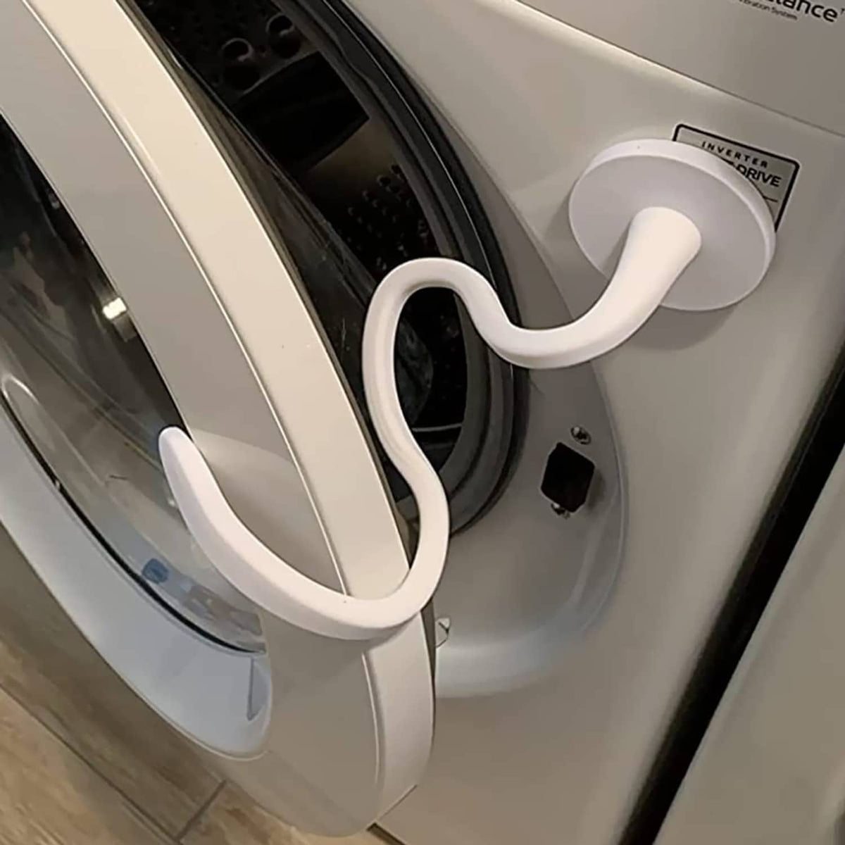 White front-load washer door prop, curved handle holding the door slightly open