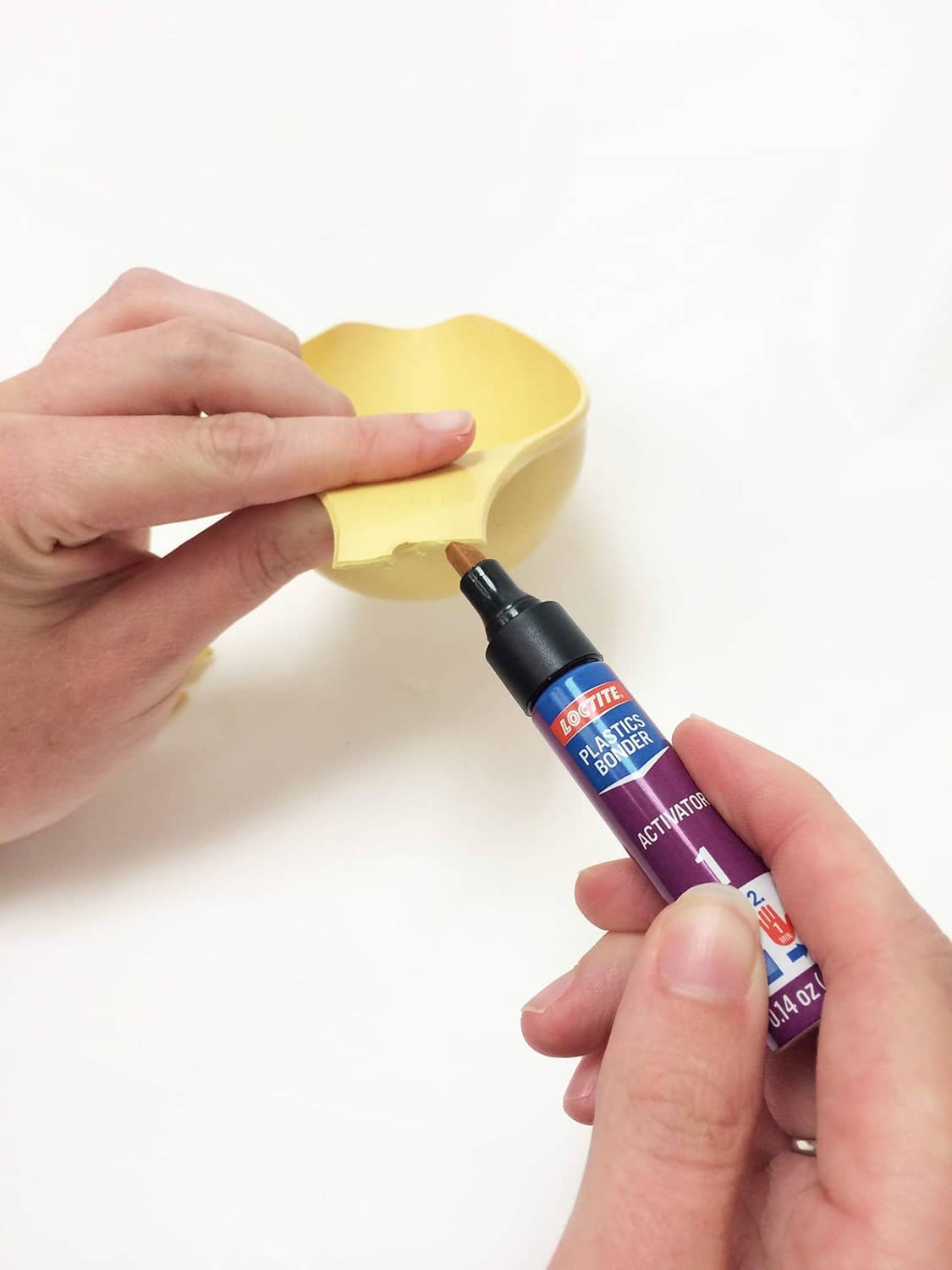 Loctite Plastics glue applicator dispensing adhesive onto yellow plastic parts