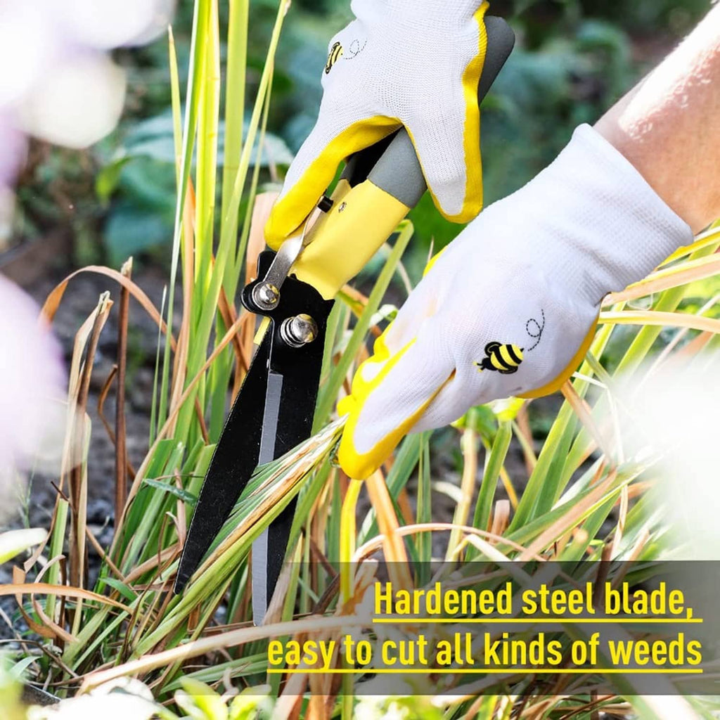 Yellow grass trimming shears with dark blades cutting lawn weeds with gloved hands