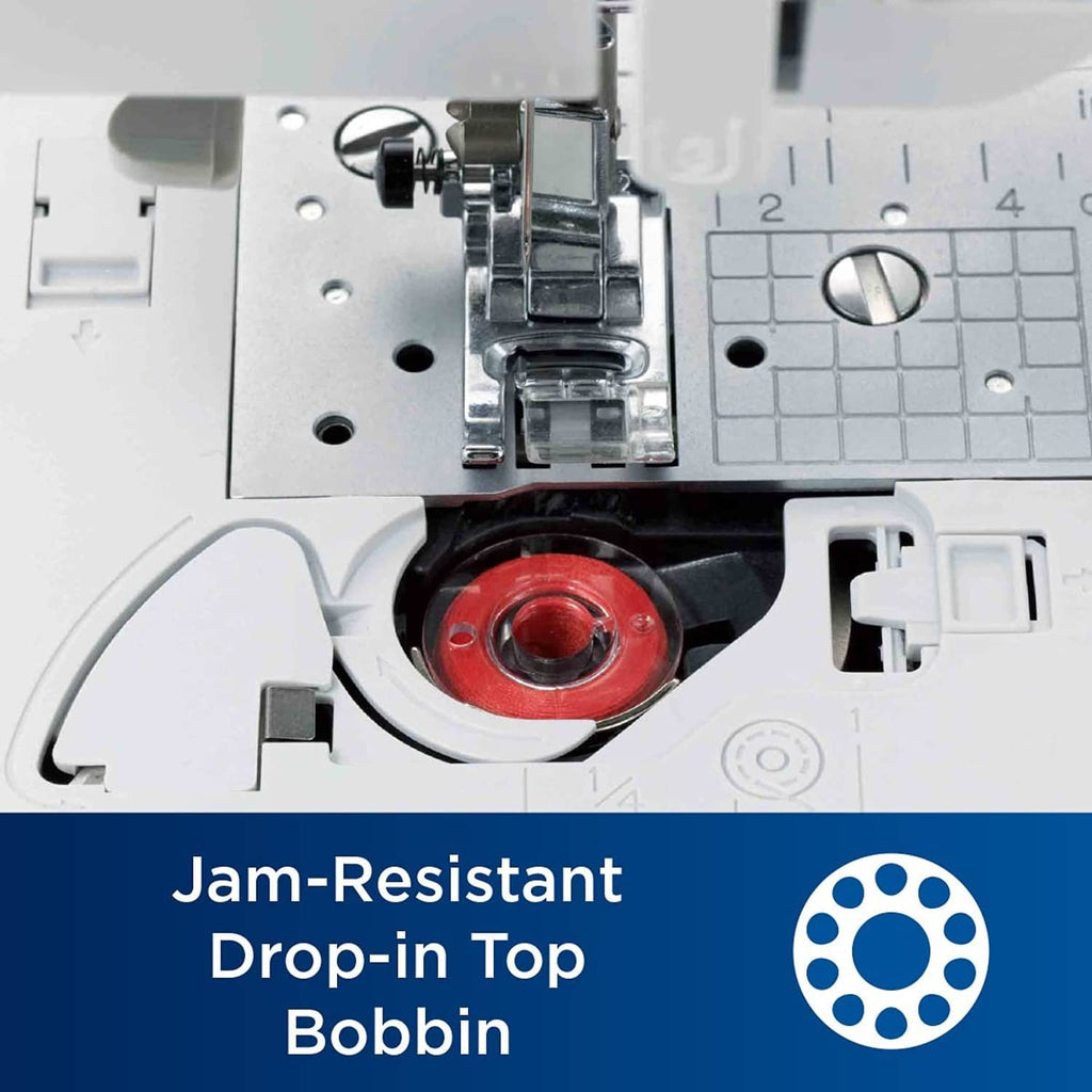 Sewing machine drop-in bobbin housing with red bobbin and needle clamp area.