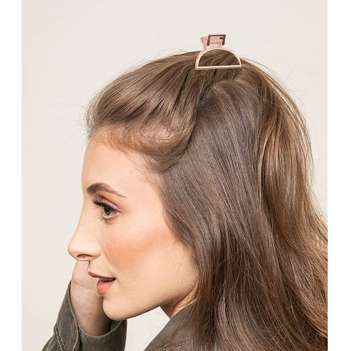 Rose-gold metal hair claw clip holding brown hair at crown, triangular frame