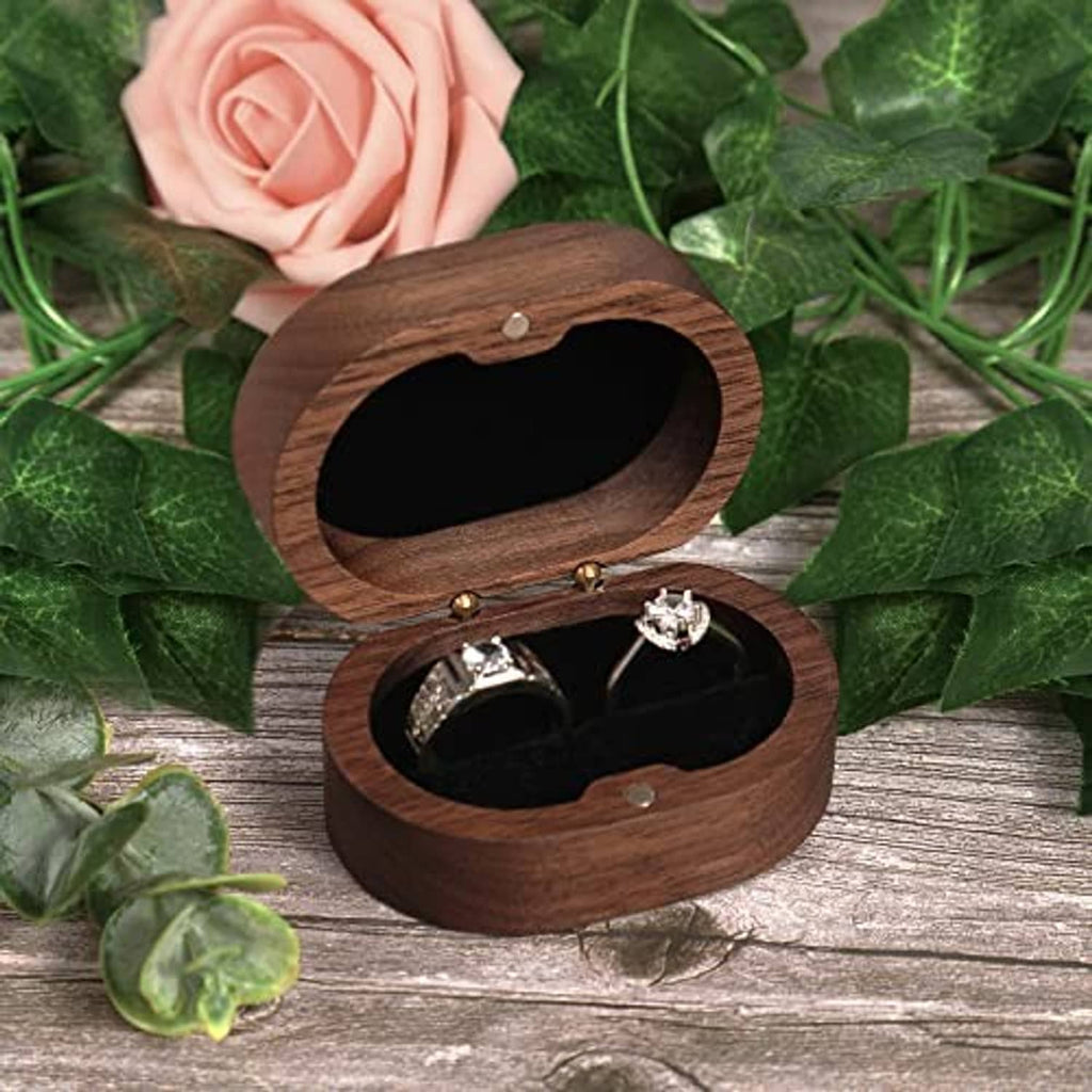 Wooden ring box with open oval window and two rings on black cushion inside