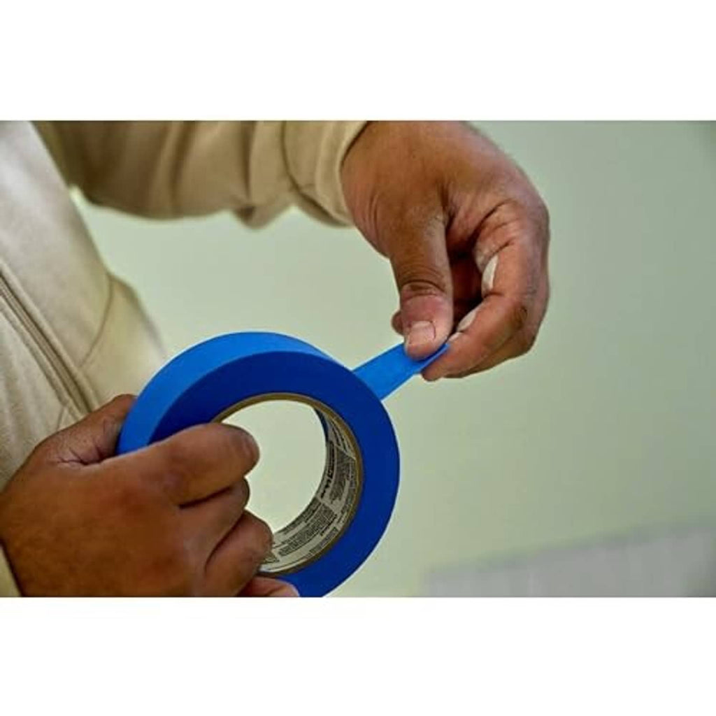 Roll of blue painter's tape being held and peeled for application