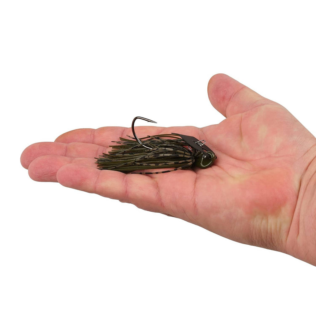 Compact bladed jig lure with dark green skirt, resting in a palm