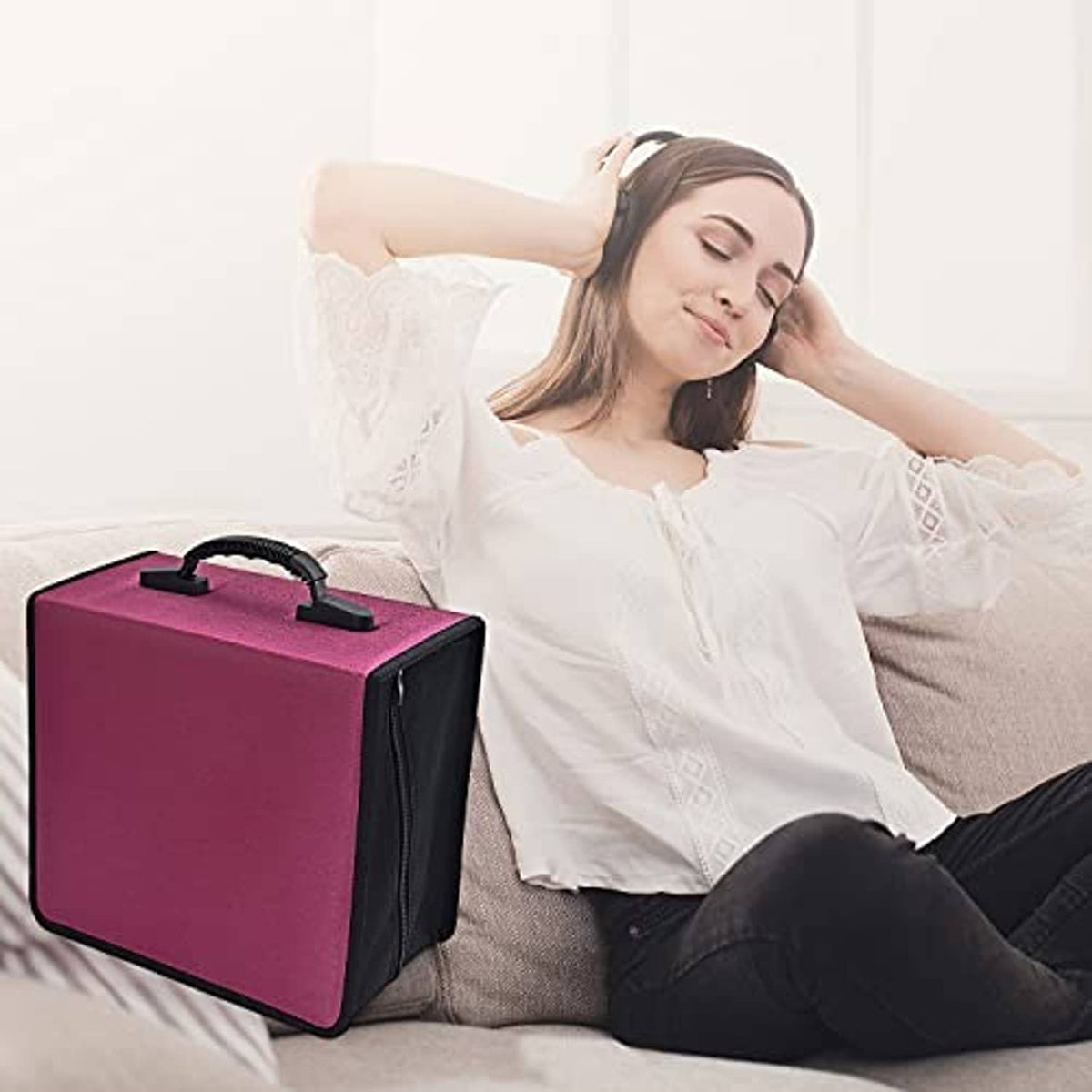 Portable red CD/DVD case with black handle beside a relaxing person