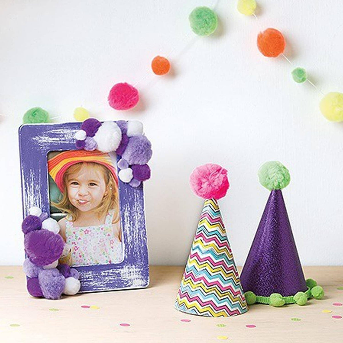 Colorful pom pom craft decorations with purple, green, pink, and yellow balls