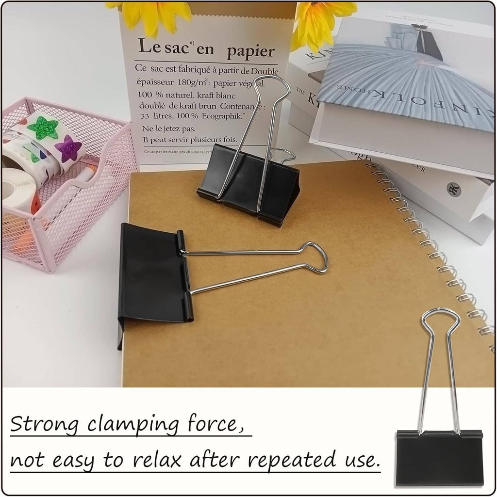 Black binder clips clamping papers to a notebook on an office desk