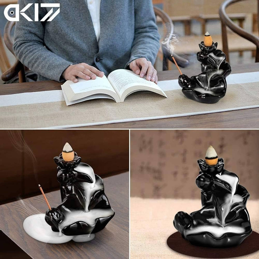 Glossy black ceramic incense holder on table with incense smoke, shown near an open book