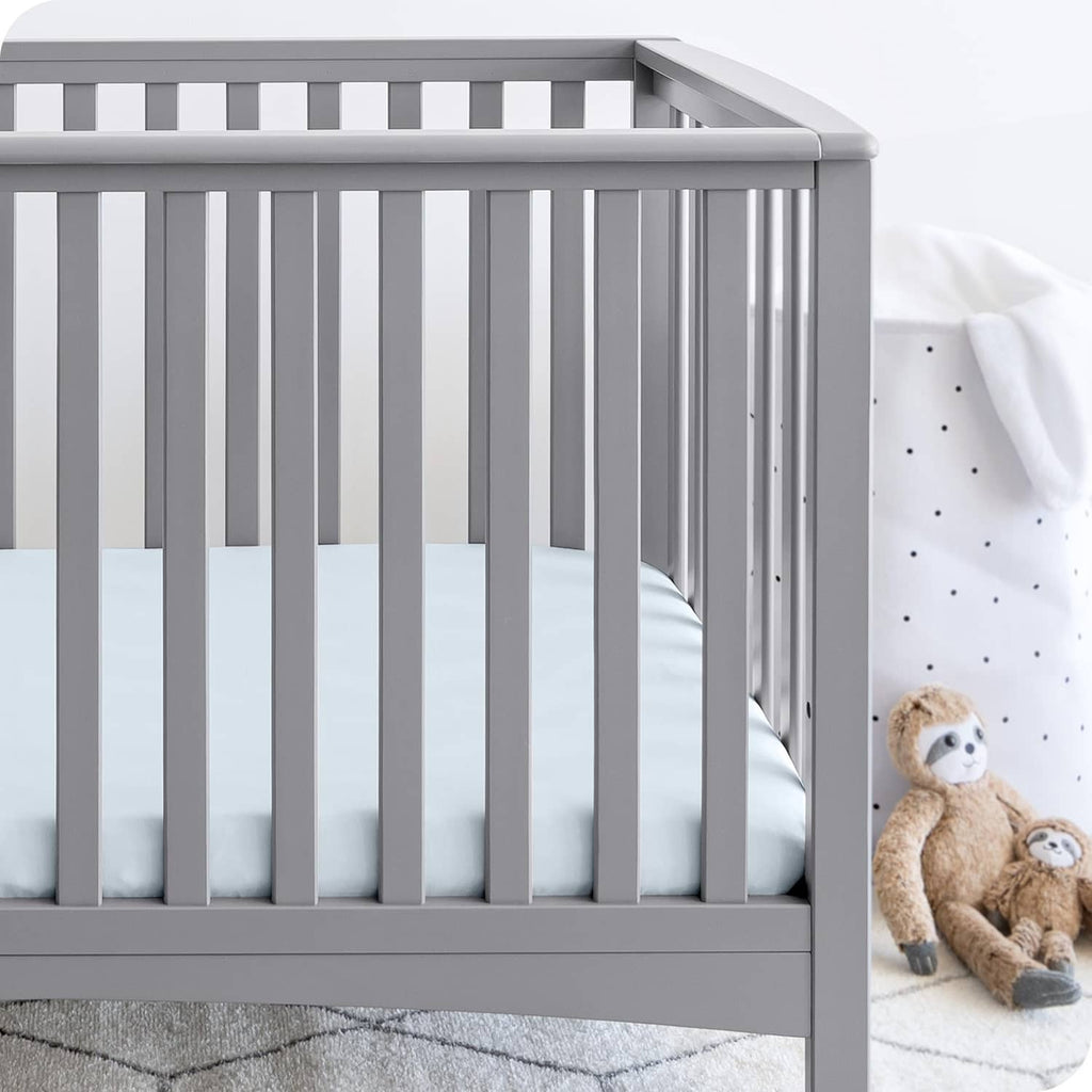 Light sky blue fitted crib sheet in place on mattress, elastic edge visible