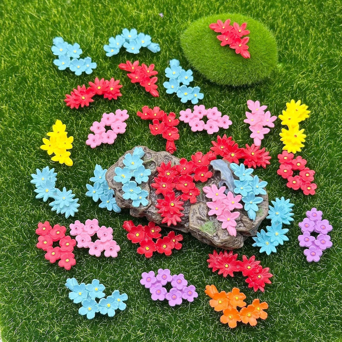 Mini resin flowers scattered on green grass with grey stone center