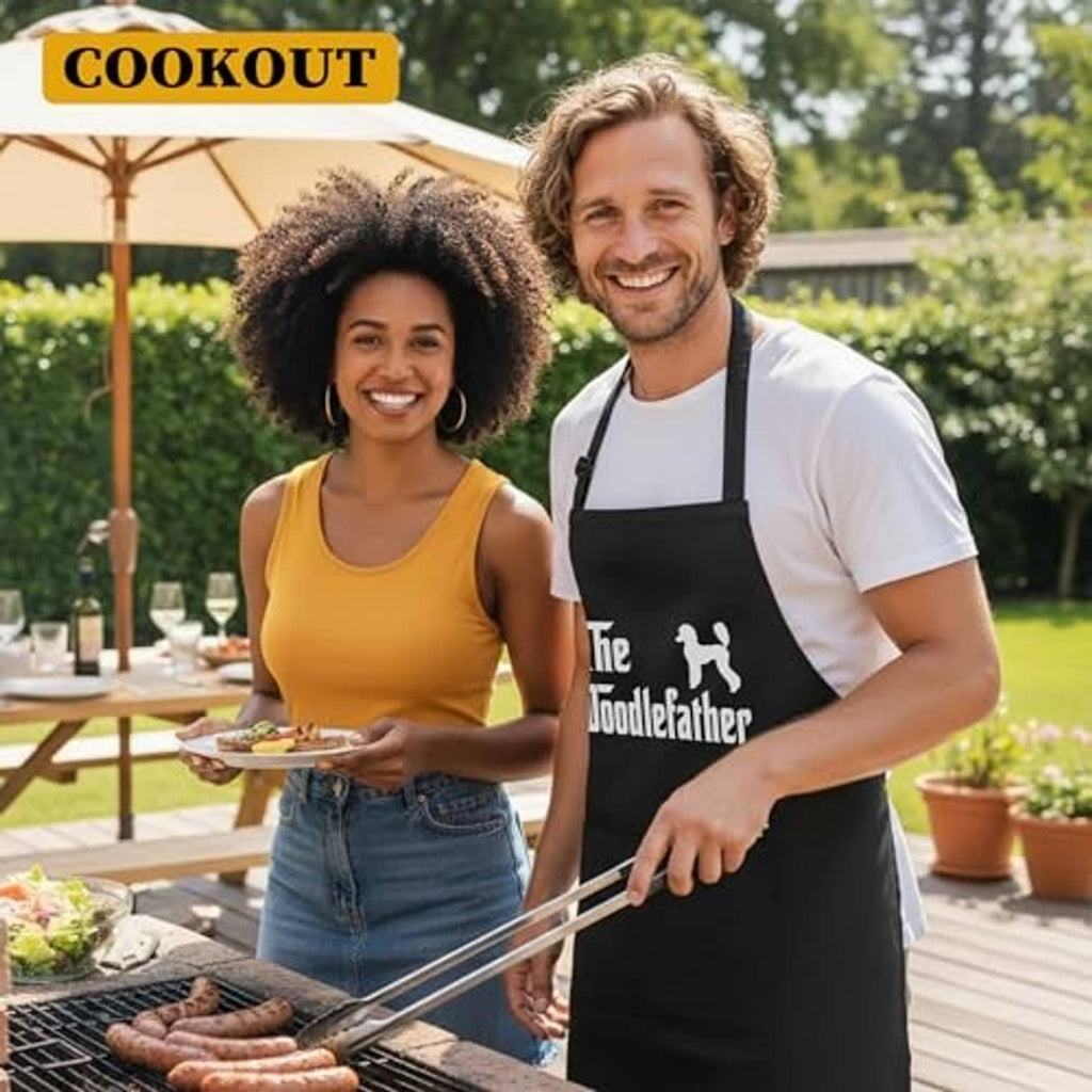 Black barbecue apron with “The Doodlefather” logo and utensil icons; adjustable neck strap