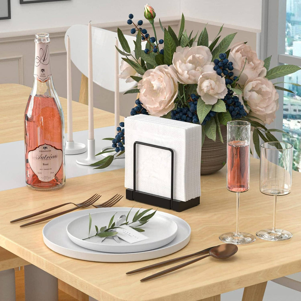 Table napkin dispenser with black stand holding white napkins, placed on tabletop.