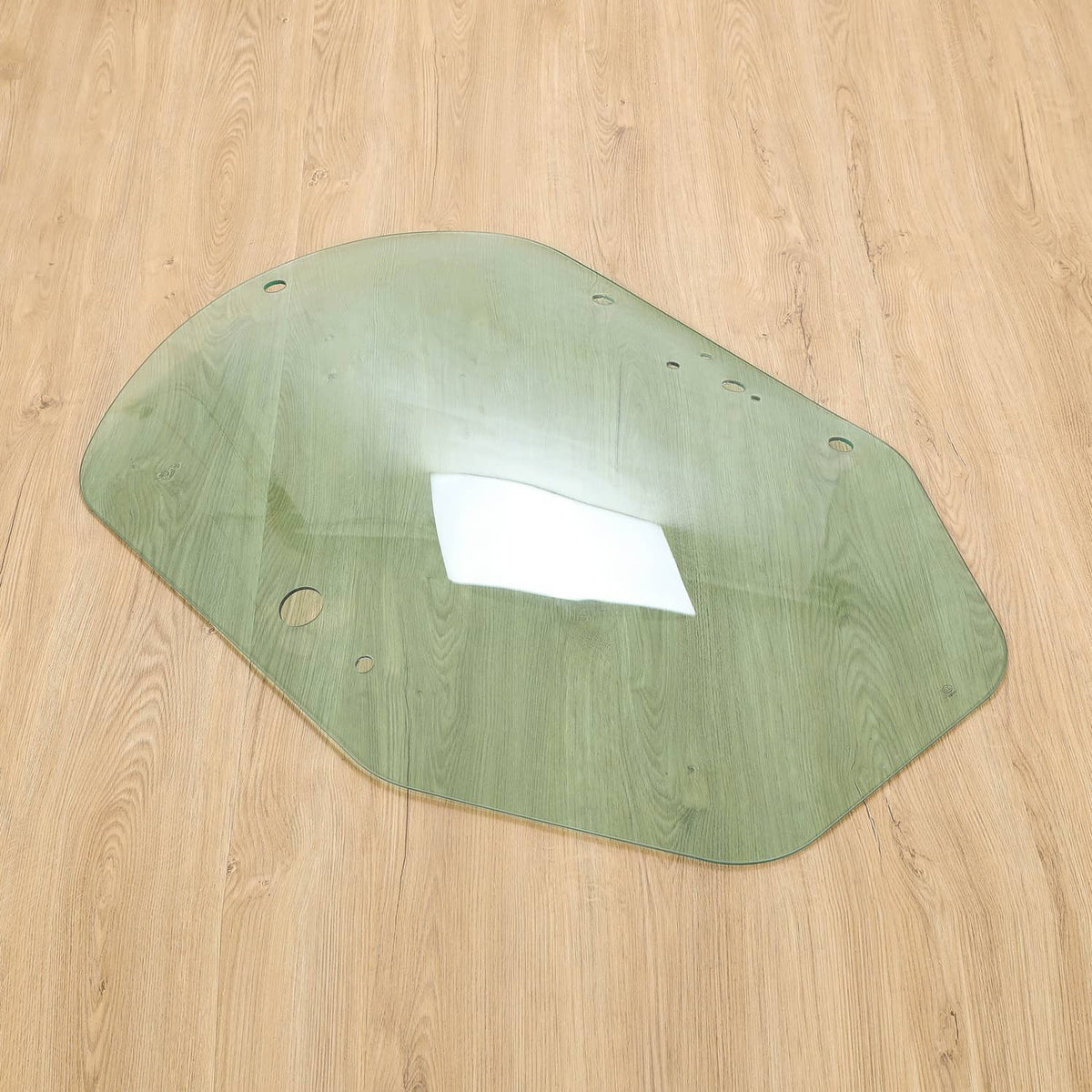 Green cab door glass panel with cutout window area and multiple mounting holes