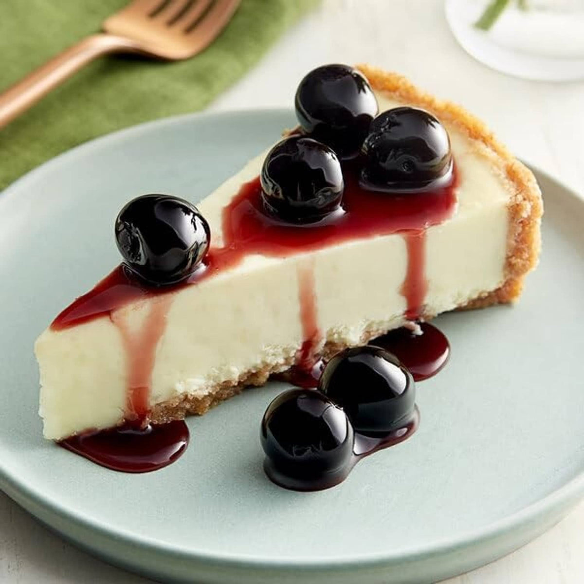 Cheesecake slice topped with dark maraschino cherries and red cherry sauce