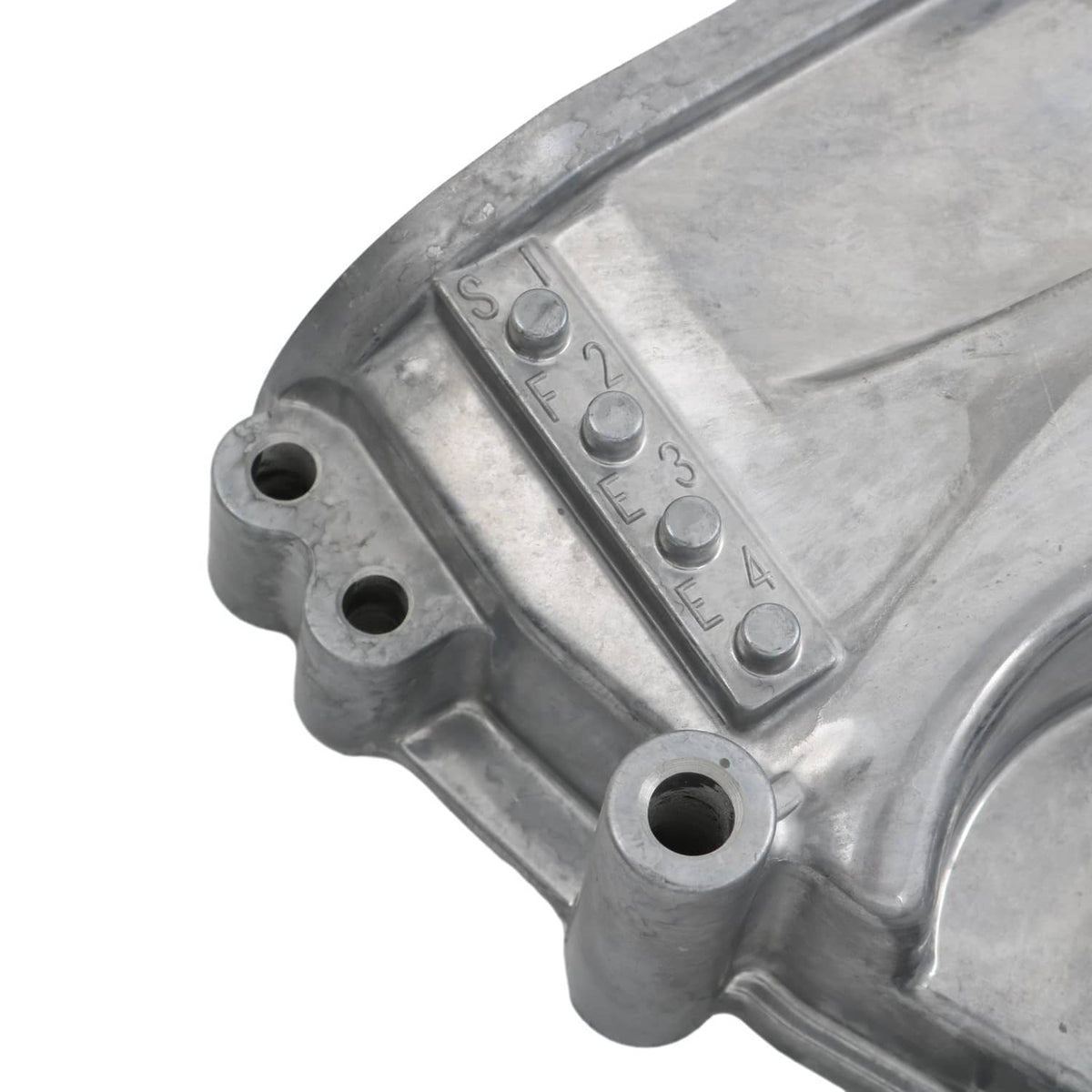 Timing cover oil pump housing close-up with stamped markings on silver metal