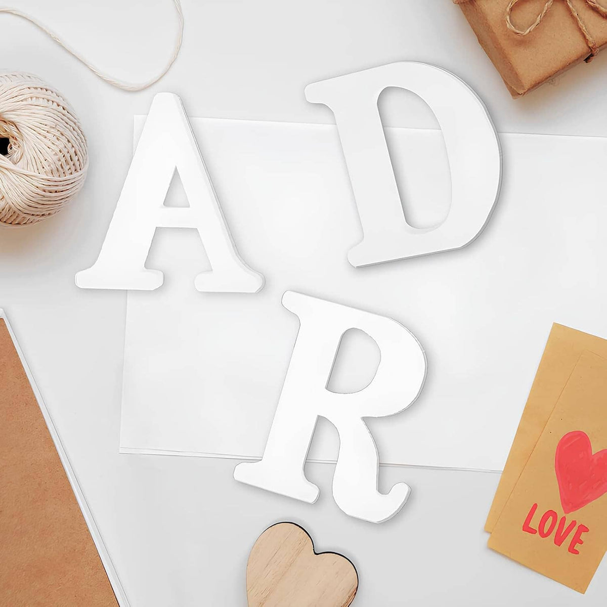 Set of white unfinished wooden letters A, D, R on a craft surface
