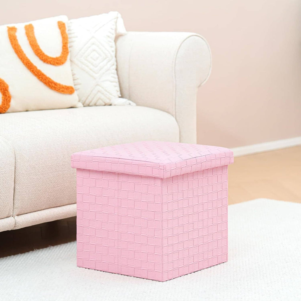 Pink cube storage ottoman on carpet with textured top and closed hinged lid.